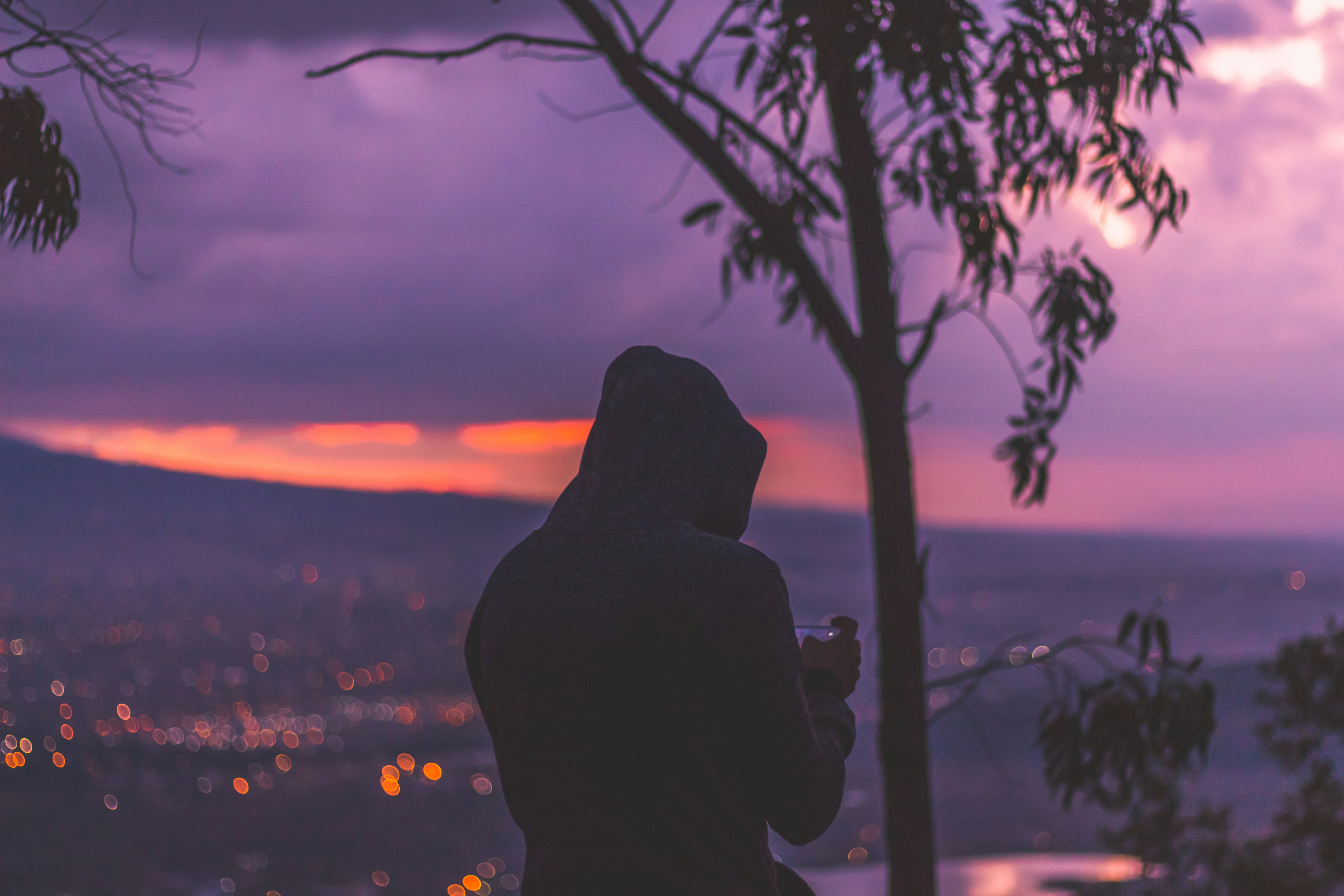 silhouette photo of man standing at the peak facing cityscape